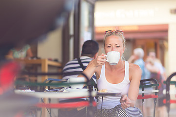 Image showing Woman drinking coffee outdoor on street.