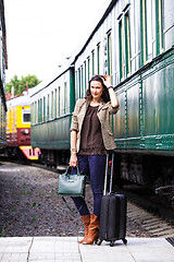 Image showing pretty woman with a suitcase and handbag standing near retro rai