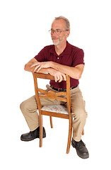 Image showing Middle age man sitting backwards on chair.