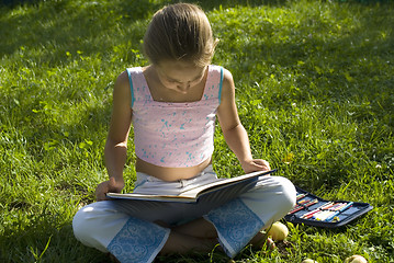 Image showing The girl draws on a meadow