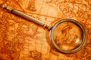 Image showing Vintage magnifying glass lies on an ancient world map