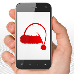 Image showing Entertainment, concept: Hand Holding Smartphone with Christmas Hat on display