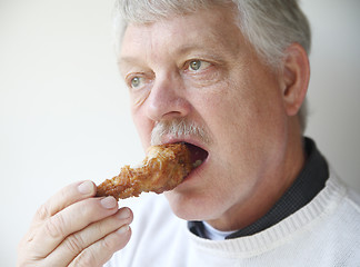 Image showing senior man eating fried chicken leg 