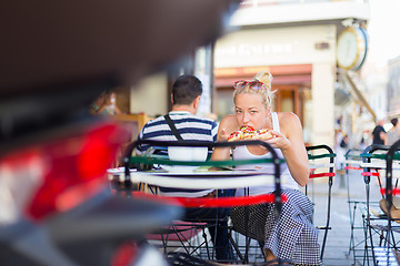 Image showing Woman eating pizza outdoor in cafeteria.