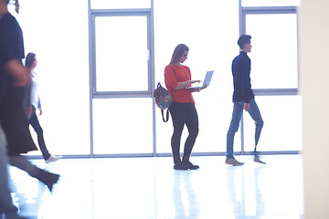 Image showing student girl standing with laptop, people group passing by