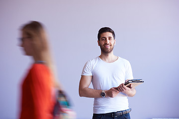 Image showing student working on tablet, people group passing by