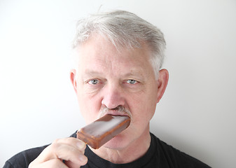 Image showing Man eats chocolate ice cream bar. 