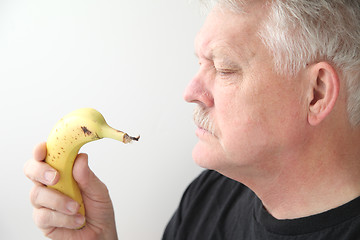 Image showing Older man holds banana.