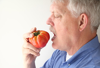 Image showing Senior man eating big tomato