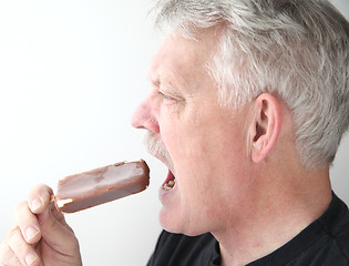 Image showing Senior man with ice cream bar profile view