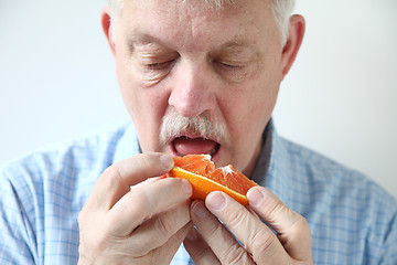 Image showing Older man eating orange