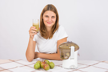 Image showing The girl is holding a glass of pear juice