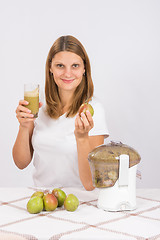 Image showing Girl holding freshly made juice in one hand and a pear in another