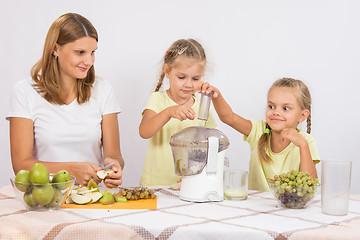 Image showing Children throw the fruit in a juicer in the care of mothers