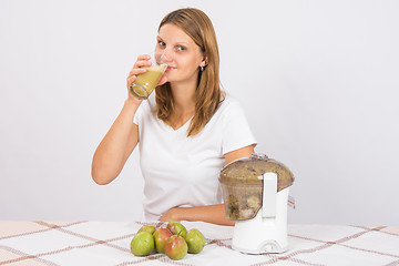 Image showing Girl freshly cooked pear juice and drink it