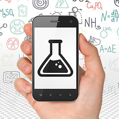 Image showing Science concept: Hand Holding Smartphone with Flask on display