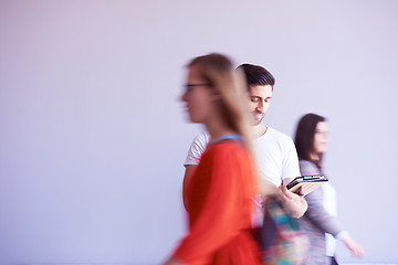 Image showing student working on tablet, people group passing by