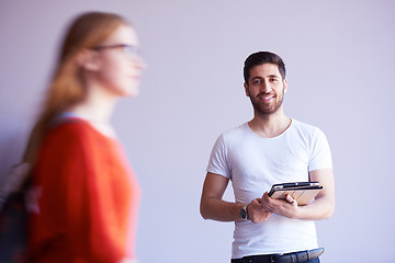 Image showing student working on tablet, people group passing by