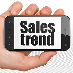 Image showing Advertising concept: Hand Holding Smartphone with Sales Trend on display