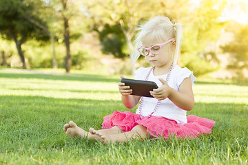 Image showing Little Girl In Grass Playing With Cell Phone