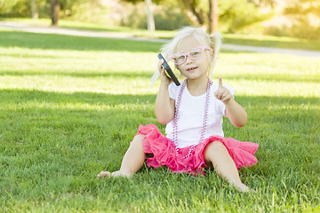 Image showing Little Girl In Grass Talking on Cell Phone