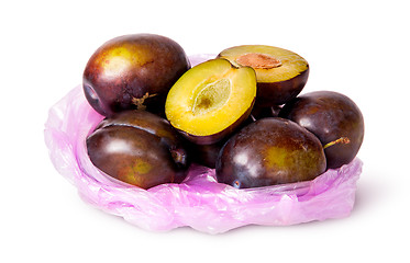 Image showing Whole and half violet plums in plastic bag