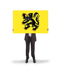 Image showing Smiling businessman holding a big card, flag of Flanders