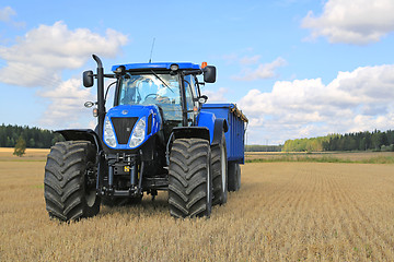 Image showing New Holland Tractor and Agricultural Trailer on Field in Autumn