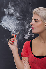 Image showing Stylish blond woman smoking an e-cigarette
