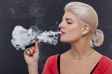 Image showing Stylish blond woman smoking an e-cigarette