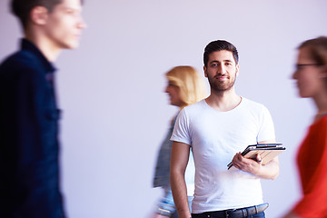 Image showing student working on tablet, people group passing by