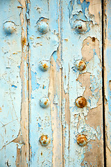 Image showing dirty stripped paint in the blue wood door   rusty nail