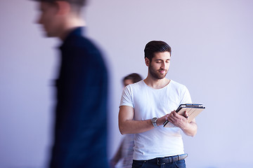 Image showing student working on tablet, people group passing by