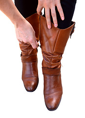 Image showing Woman holds her brown leather boots while zipping them up