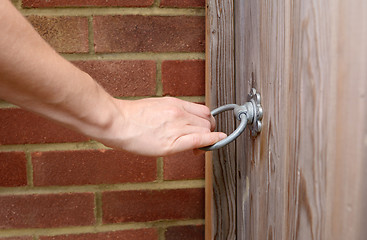 Image showing Woman turns a metal ring handle to open a gate