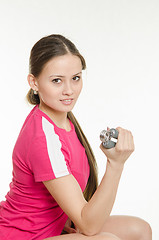 Image showing Sportswoman sitting and flexing arm muscles expanders