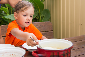 Image showing Girl scoop ladle porridge from the pot