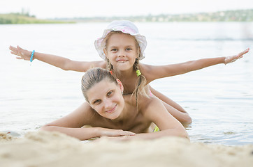 Image showing Mom and daughter lying on the sand on the bank of the river