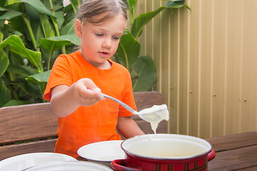 Image showing Girl at breakfast porridge scoop ladle