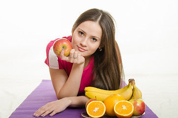 Image showing Sportswoman lying on a mat with fruit in their hands