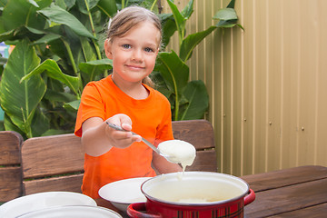 Image showing Girl with a smile imposes semolina his plate