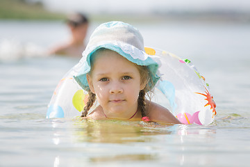 Image showing Concentrated four-year girl with a circle floating in the river