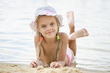 Image showing Six year old girl lying on the sand on the beach