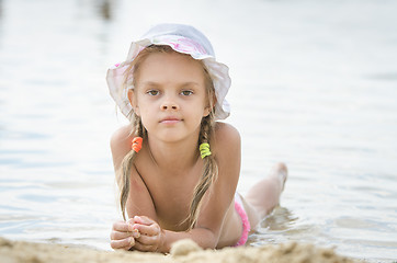 Image showing The girl in panama lying on the river bank