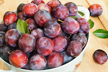 Image showing Large plum in a ceramic vase on the table.