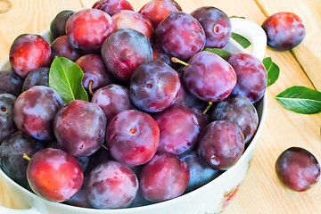 Image showing Large plum in a ceramic vase on the table.