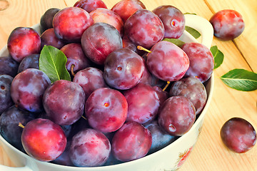 Image showing Large plum in a ceramic vase on the table.