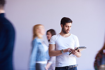 Image showing student working on tablet, people group passing by