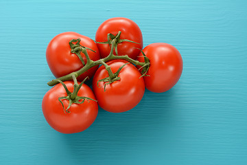 Image showing Fresh tomatoes on the vine on a blue wooden surface