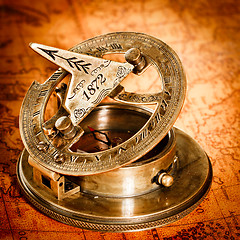 Image showing Vintage compass lies on an ancient world map.